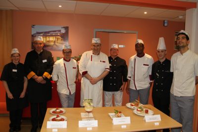 Un groupe de chefs posant devant une table avec de la nourriture dessus.