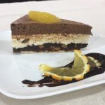 Un morceau de gâteau au chocolat sur une assiette avec une tranche d'orange.