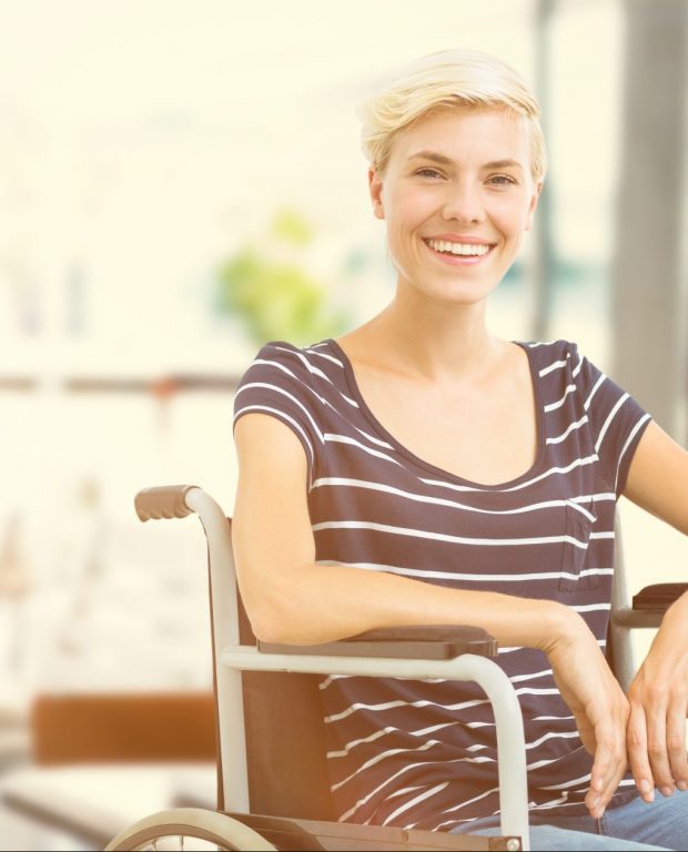 Une femme est assise dans un fauteuil roulant et sourit dans un établissement spécialisé dans la restauration pour personnes en situation de handicap.