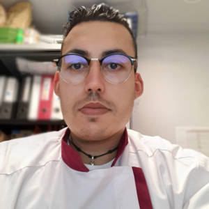 Un homme à lunettes prend un selfie dans une cuisine.