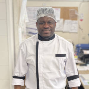 Un homme en uniforme de chef debout dans une cuisine.