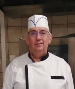 Un homme en uniforme de chef debout dans une cuisine.