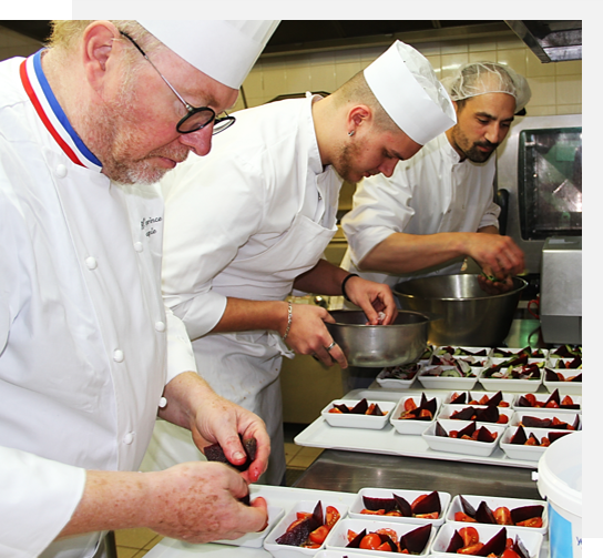 Un groupe de chefs préparant des plats dans une cuisine.