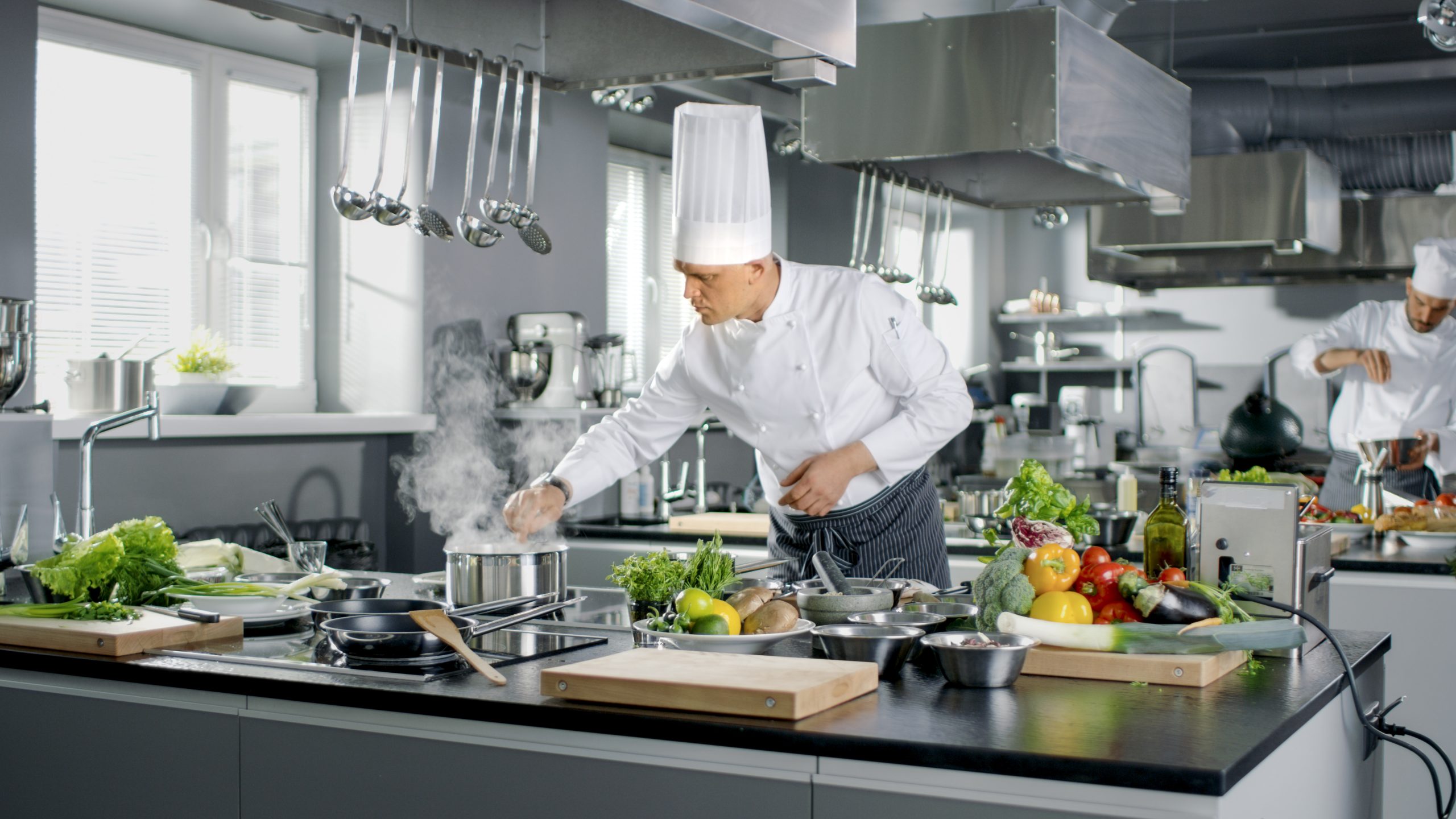 Deux chefs préparant des plats dans une cuisine.