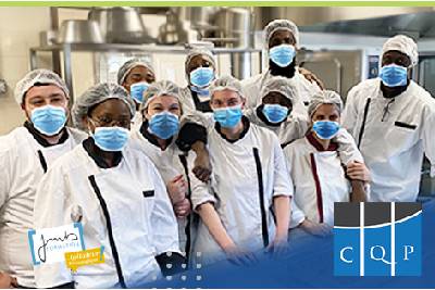 Un groupe de personnes portant des masques dans une cuisine pour développer les compétences techniques grâce au CQP.