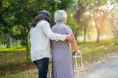 Deux femmes âgées marchant sur un chemin avec une marchette.