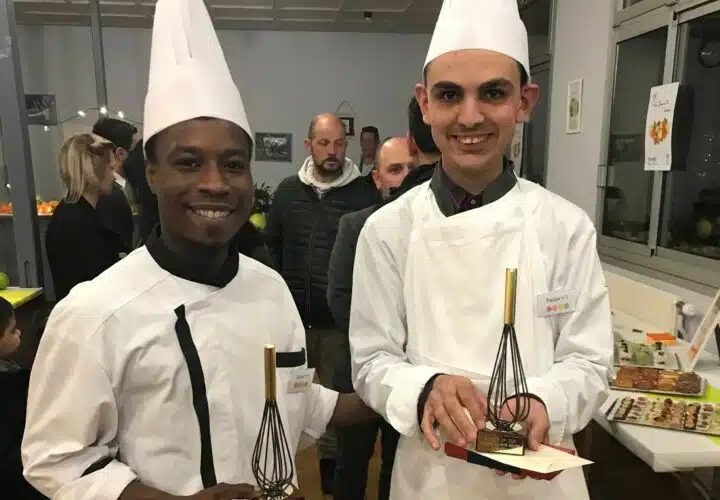 Deux chefs participants à un concours culinaire pour les personnes en situation de handicap, posant pour une photo dans une cuisine.