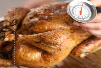 Une personne tenant un thermomètre pour vérifier la température de cuisson d'un poulet rôti